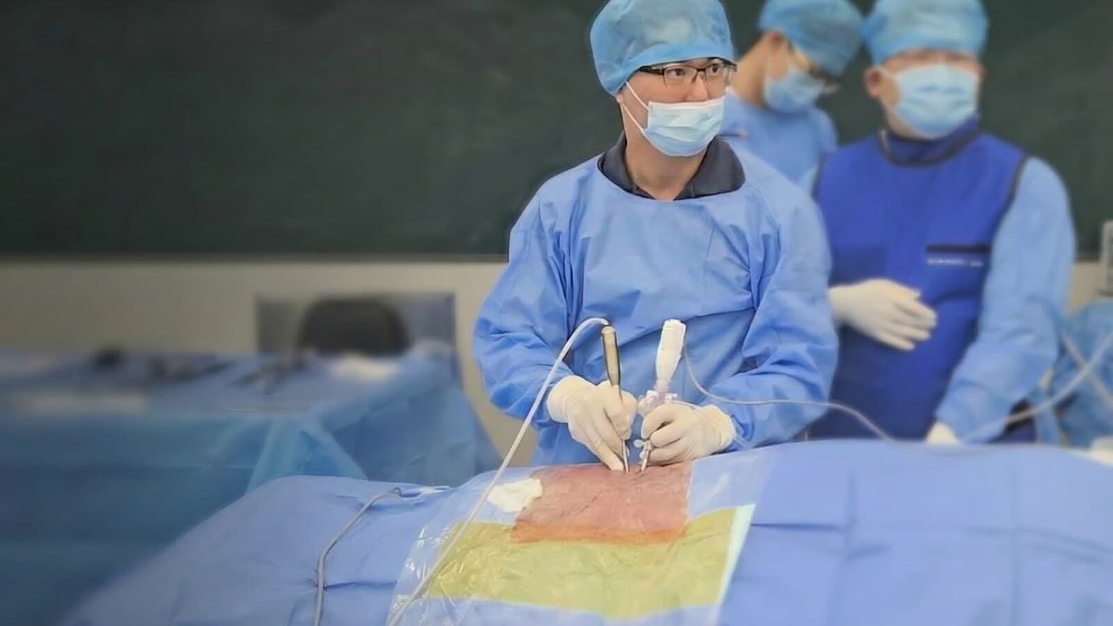 Surgeon holding the TISE scope pencil-style in a straight grip, handle detached, during a training session