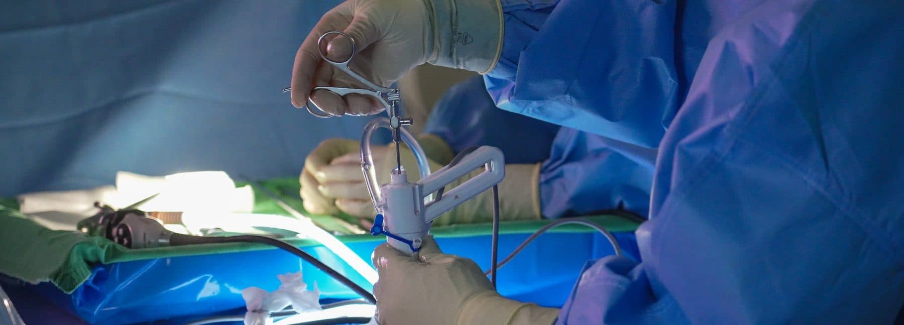 Surgeon's gloved hands holding the TISE scope by its pistol grip during a procedure