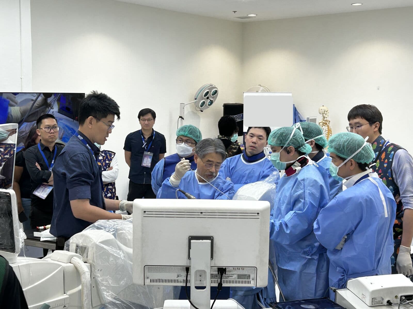 Faculty surgeon demonstrating endoscopic technique on a training model while trainees gather around the monitor